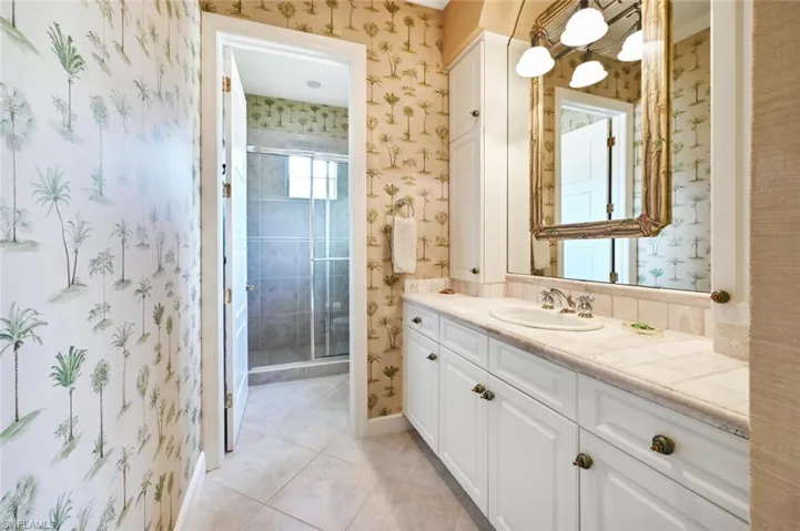 Bathroom featuring tile patterned flooring, vanity, and a shower with door