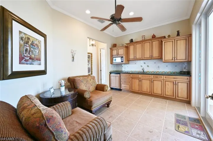 Kitchen with built in microwave, ceiling fan, decorative backsplash, light tile patterned flooring, and crown molding
