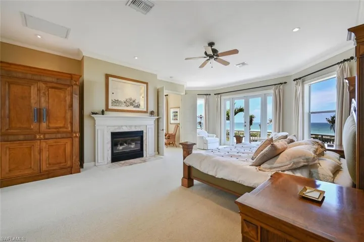 Bedroom featuring ornamental molding, access to exterior, light colored carpet, and a fireplace