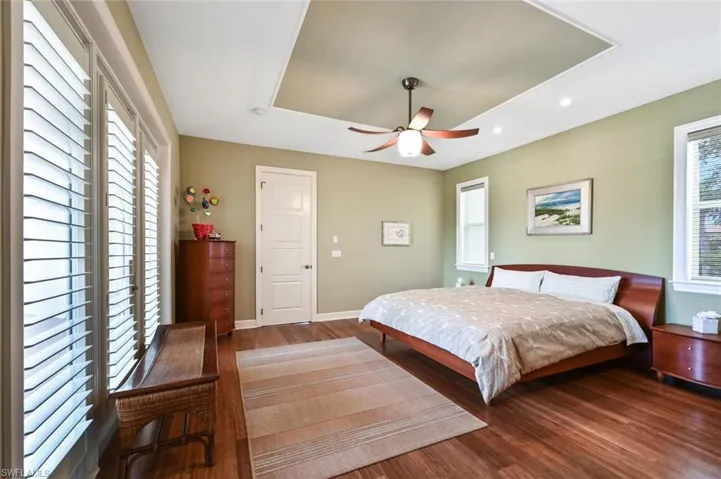 Bedroom with ceiling fan, a raised ceiling, and hardwood / wood-style floors