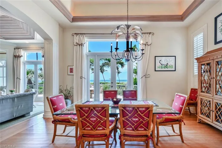 Dining room with hardwood / wood-style flooring, a raised ceiling, french doors, and a notable chandelier
