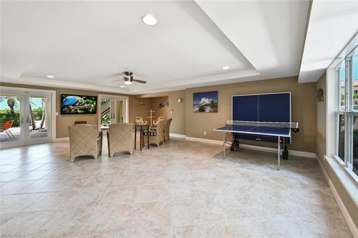 Recreation room with french doors, light tile patterned floors, ceiling fan, and a raised ceiling
