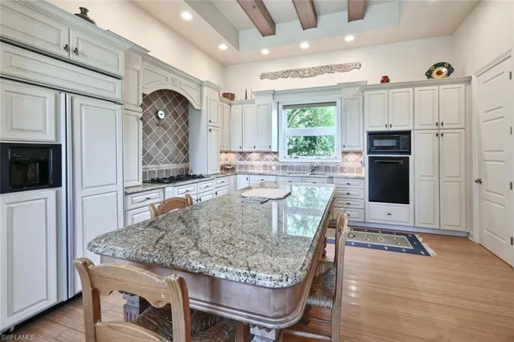 Kitchen featuring a center island, black appliances, light stone counters, and backsplash