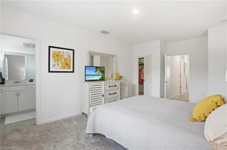 Carpeted primary bedroom with walk-in closet and en suite bathroom