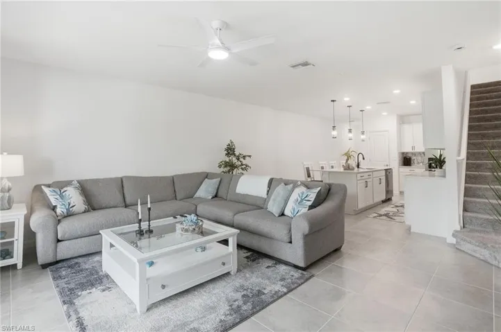 Open-concept living area featuring a modern ceiling fan, large format tile flooring, and neutral wall tones