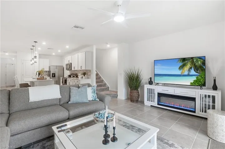 Open-concept living area featuring light-toned tile flooring and recessed lighting