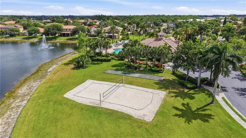 Lakefront recreational area featuring a sand volleyball court, bocce ball court, and verdant landscaping