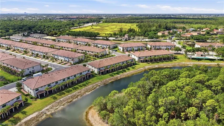 Aerial perspective showcasing a residential community with numerous two-story townhomes featuring tile roofs and light-colored exteriors