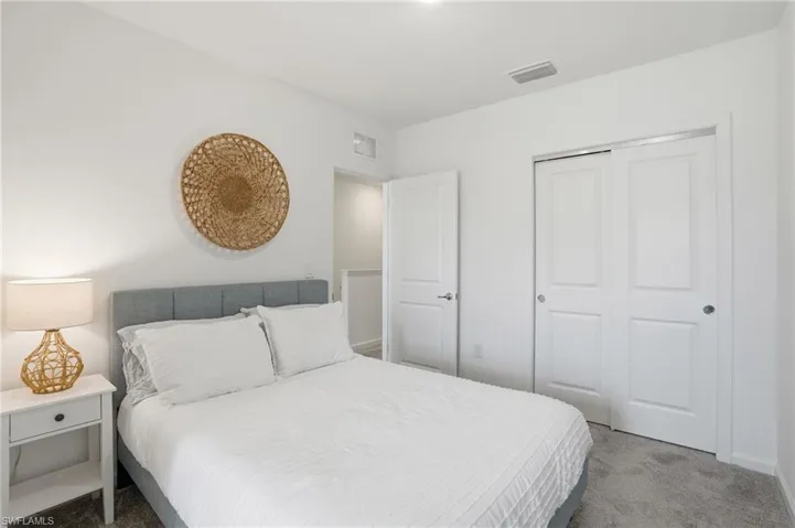 Bedroom with white walls, gray carpet, and white bi-fold closet doors