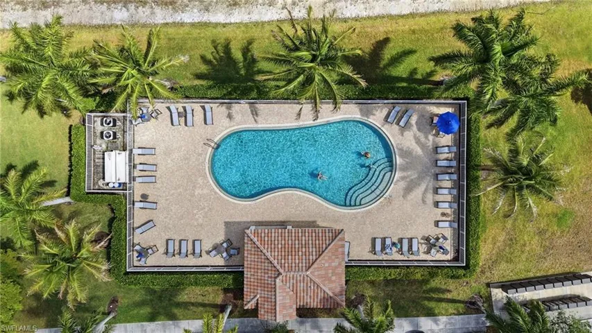 Curved swimming pool with integrated steps, surrounded by a textured hardscape deck
