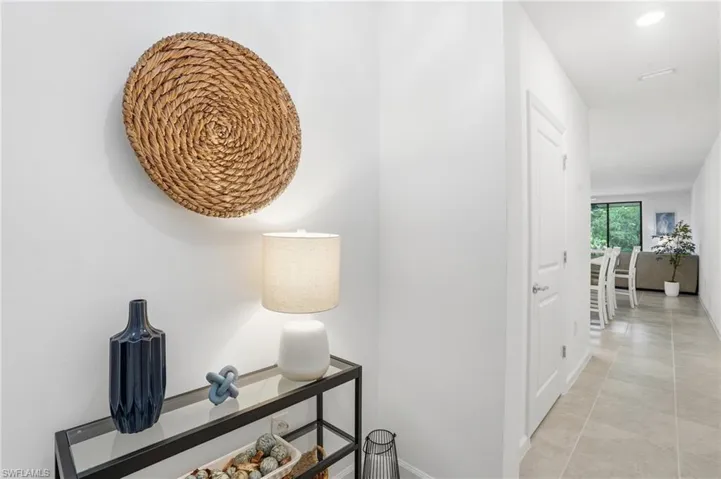Spacious hallway with light-toned tile flooring, recessed ceiling lighting, and solid core doors