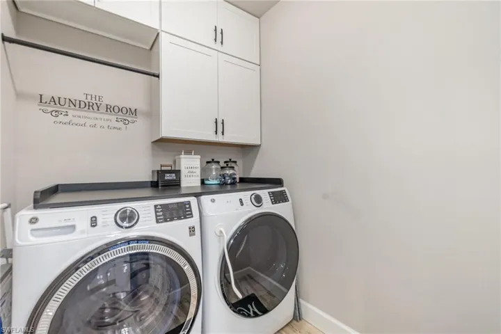 Front load washer/dryer with cabinetry and room to hang clothing.