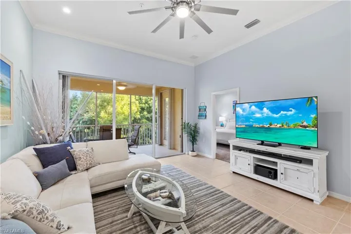 Living room featuring crown molding, light tile patterned floors, and ceiling fan