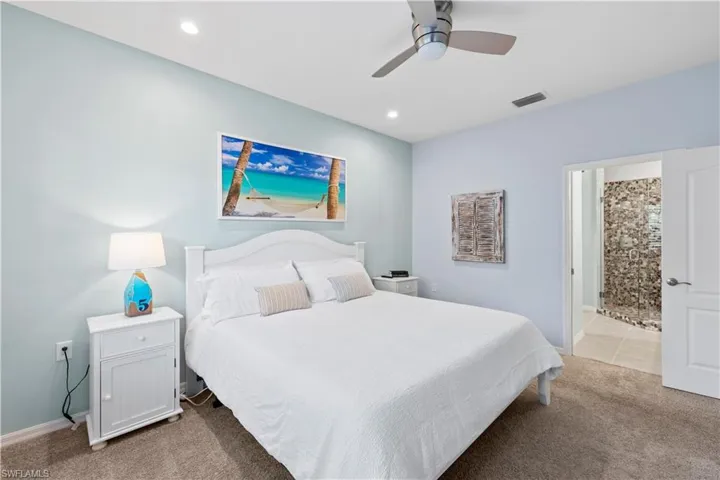 Bedroom with a closet, light colored carpet, and a ceiling fan