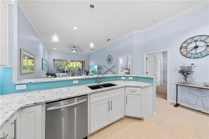 Kitchen featuring stainless steel dishwasher, pendant lighting, ceiling fan, white cabinets, and open floor plan