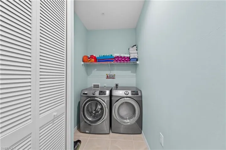 Washroom with light tile patterned floors and washer and dryer