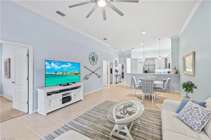 Living room featuring light tile patterned floors, a ceiling fan, and ornamental molding