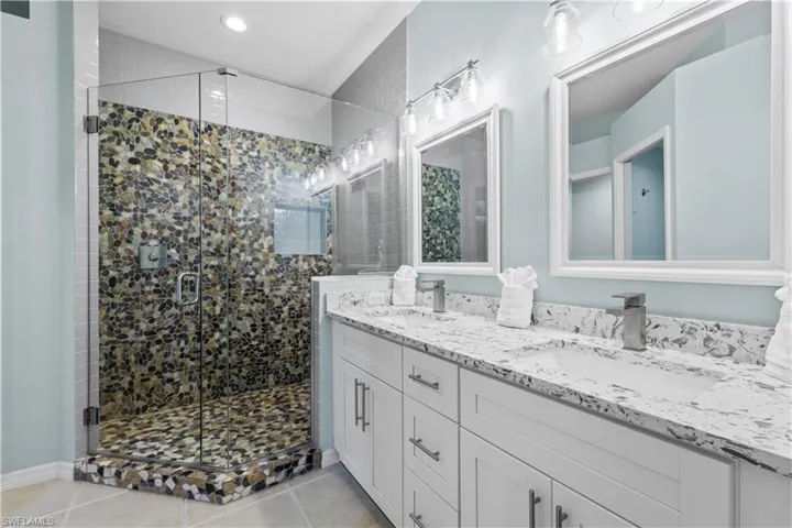 Full bath featuring double vanity, a stall shower, and light tile patterned flooring