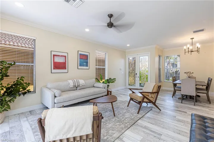 Living area featuring light wood-style floors, visible vents, crown molding, and baseboards