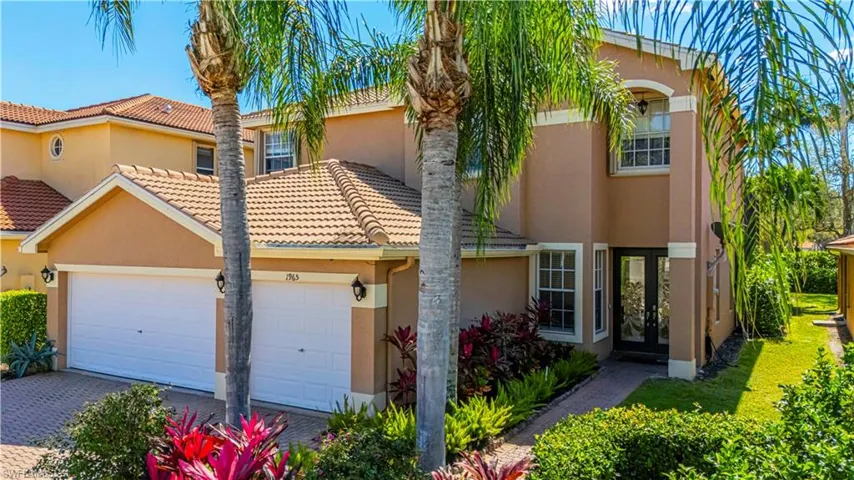 View of front facade with a tiled roof, an attached garage, decorative driveway, french doors, and stucco siding
