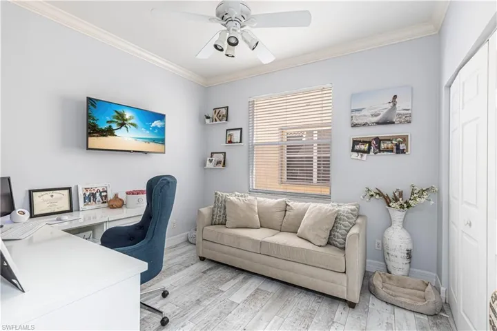 Office area with a ceiling fan, crown molding, light wood-style flooring, and baseboards