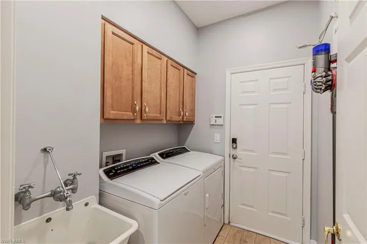 Laundry area featuring a sink, washing machine and clothes dryer, cabinet space, and light wood-style floors