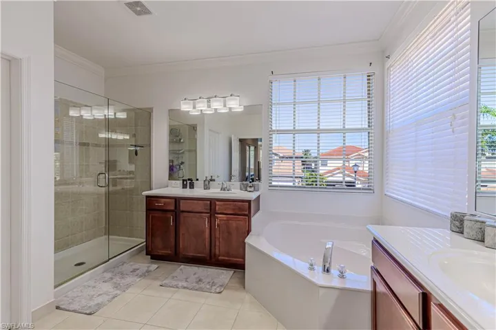 Full bathroom featuring two vanities, a sink, visible vents, a shower stall, and crown molding
