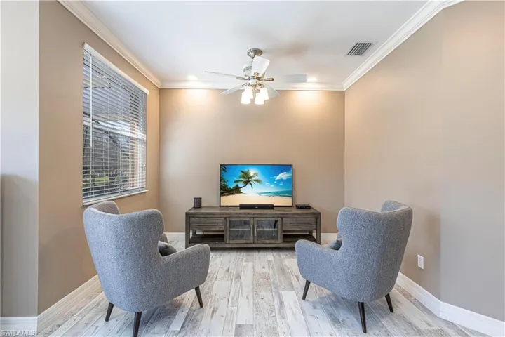 Living area featuring visible vents, crown molding, baseboards, and wood finished floors