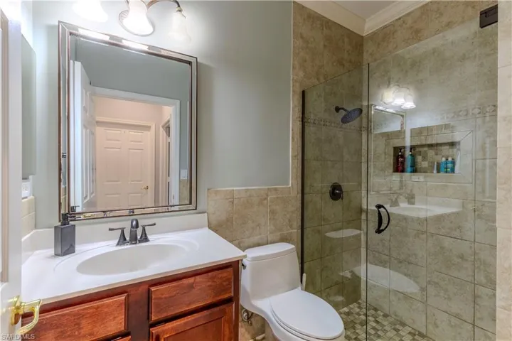 Full bathroom featuring toilet, a stall shower, crown molding, and vanity