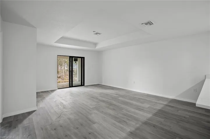 Unfurnished room featuring a raised ceiling and wood finished floors