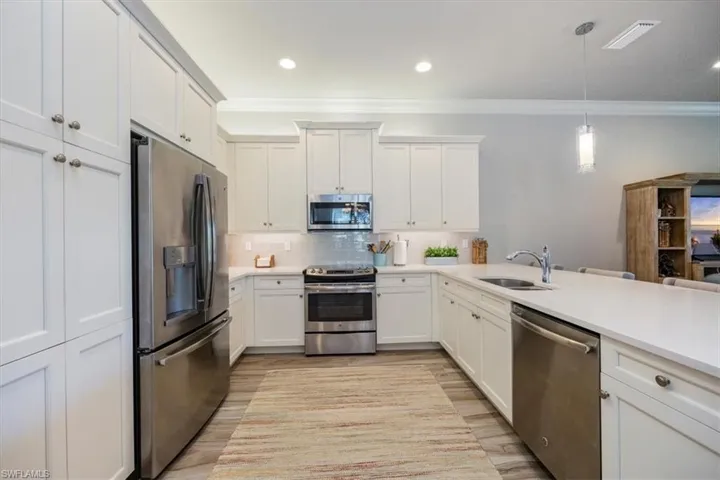 Kitchen featuring ornamental molding, a sink, tasteful backsplash, stainless steel appliances, and light countertops
