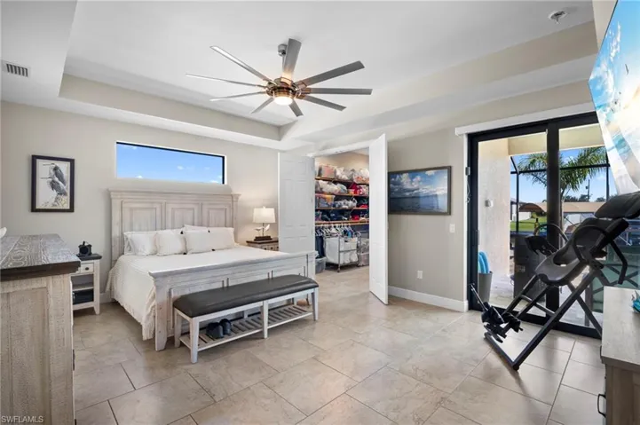 Bedroom featuring a walk in closet, access to exterior, a raised ceiling, and ceiling fan