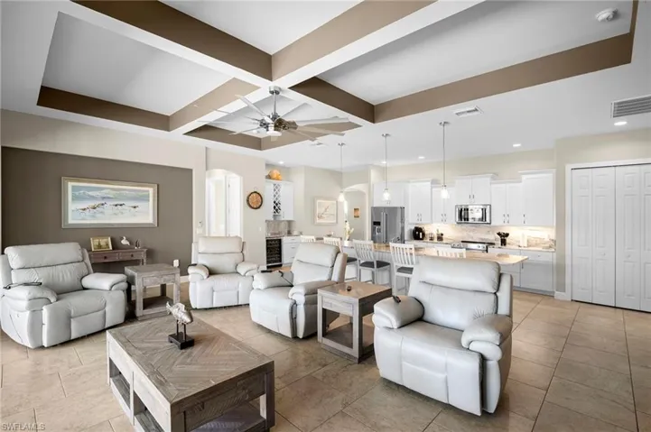 Living area featuring arched walkways, coffered ceiling, wine cooler, ceiling fan, and beam ceiling