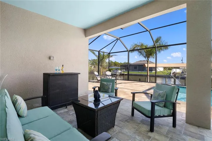 View of patio / terrace with a lanai, a sunroom, an outdoor pool, a water view, and an outdoor living space