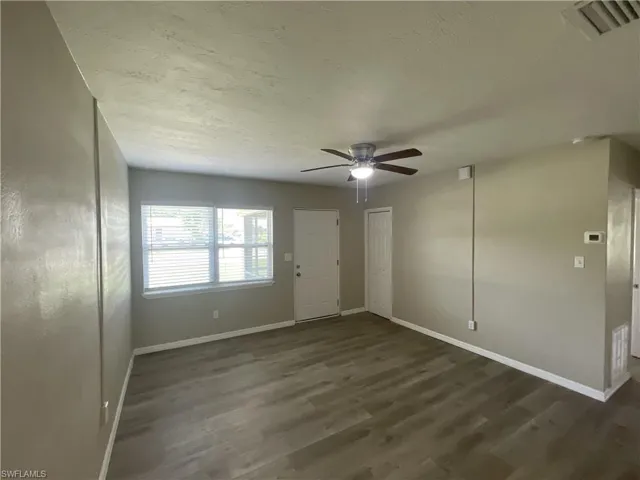 Living room featuring dark wood-style flooring and ceiling fan