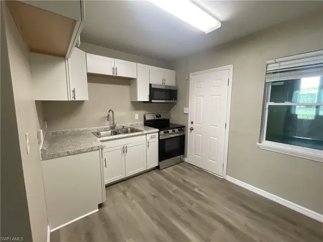 Kitchen with stainless steel appliances, white cabinetry, and light countertops