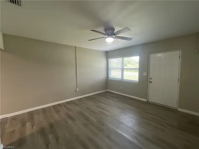 Living room featuring ceiling fan and dark wood-style flooring