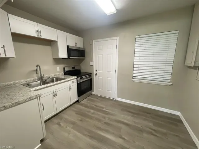 Kitchen with stainless steel appliances,  white cabinetry, and light countertops