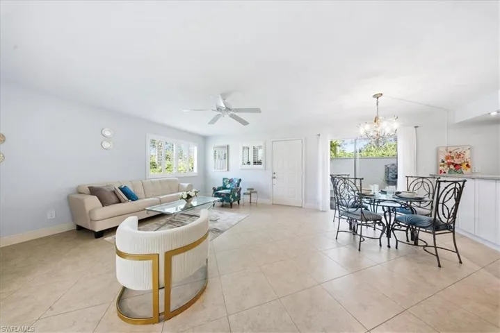 Living room with healthy amount of natural light, a ceiling fan, a chandelier, and light tile patterned floors