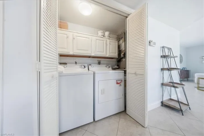 Laundry room featuring cabinet space, light tile patterned flooring, and washer and dryer