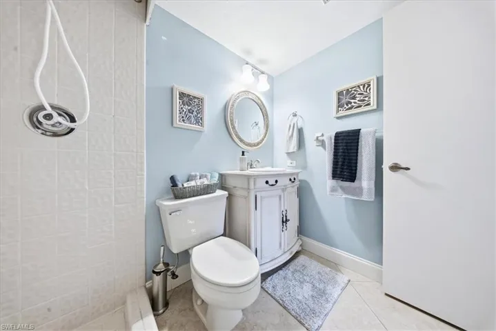 Bathroom featuring a tile shower, vanity, and light tile patterned floors