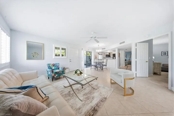 Tiled living area with a ceiling fan and a chandelier
