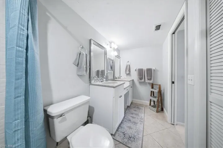 Full bath featuring vanity, light tile patterned floors, a closet, and a shower with shower curtain