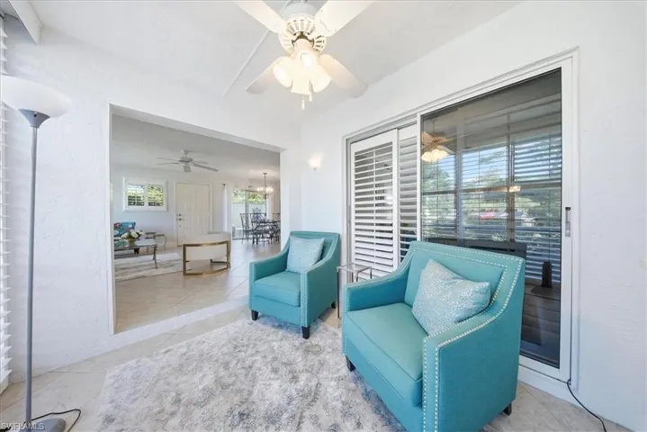 Sitting room with a textured wall, tile patterned floors, a ceiling fan, and a chandelier