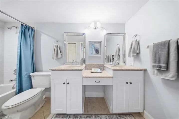 Bathroom featuring shower / bath combo with shower curtain, light tile patterned flooring, and vanity