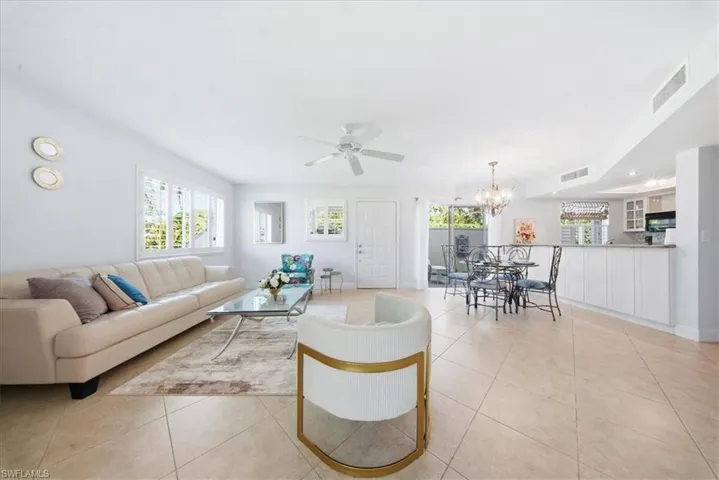 Living area with light tile patterned floors, a ceiling fan, and a chandelier