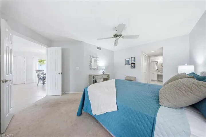 Tiled bedroom featuring carpet, a ceiling fan, and ensuite bath