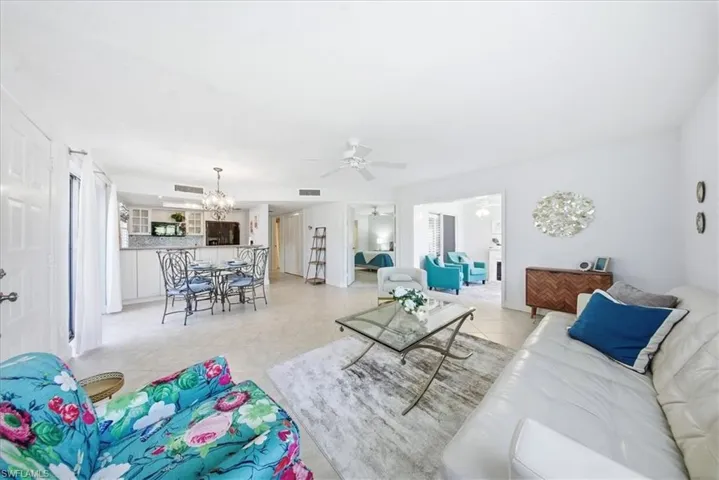 Living room with ceiling fan, light tile patterned floors, and a chandelier