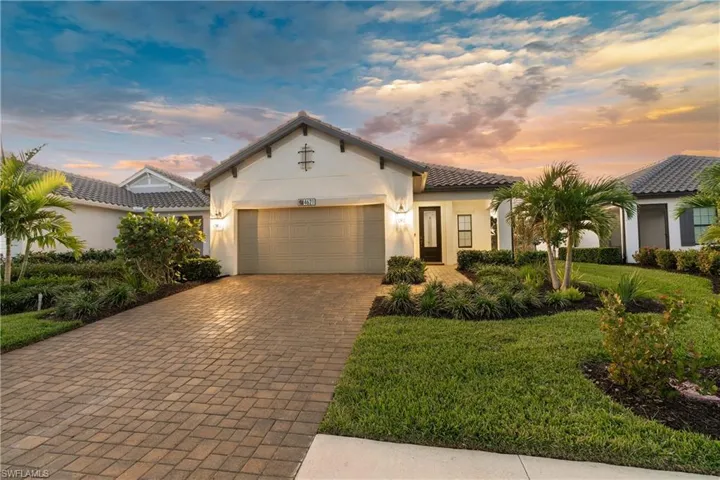 Mediterranean / spanish-style home featuring stucco siding, decorative driveway, an attached garage, a tiled roof, and a front yard