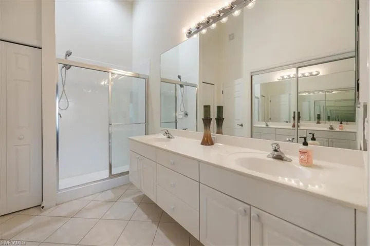 Bathroom featuring a towering ceiling, tile patterned floors, a shower with shower door, and vanity